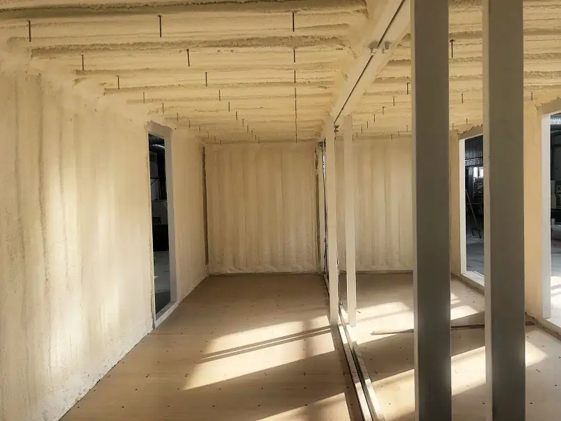 Closed-cell spray foam fills the corrugations and forms a continuous layer against the steel.